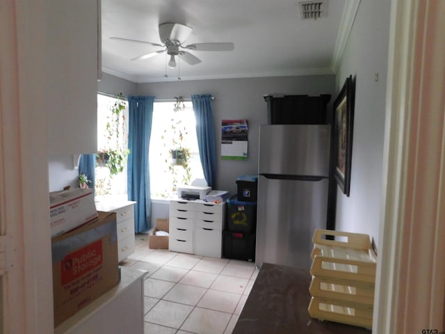 kitchen with light tile patterned flooring, freestanding refrigerator, a ceiling fan, visible vents, and ornamental molding