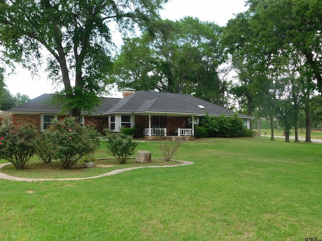ranch-style house featuring a porch, a chimney, and a front yard