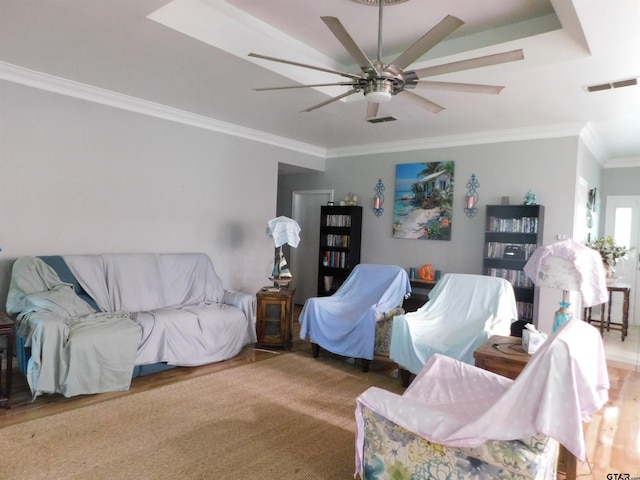 living room featuring crown molding, ceiling fan, visible vents, and wood finished floors