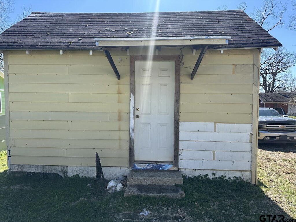 doorway to property featuring roof with shingles