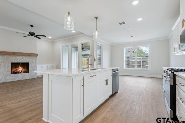 7130 Alexander Dr, Tyler, TX 75707 - kitchen with stainless steel appliances, a fireplace, light wood-type flooring, light countertops, and crown molding