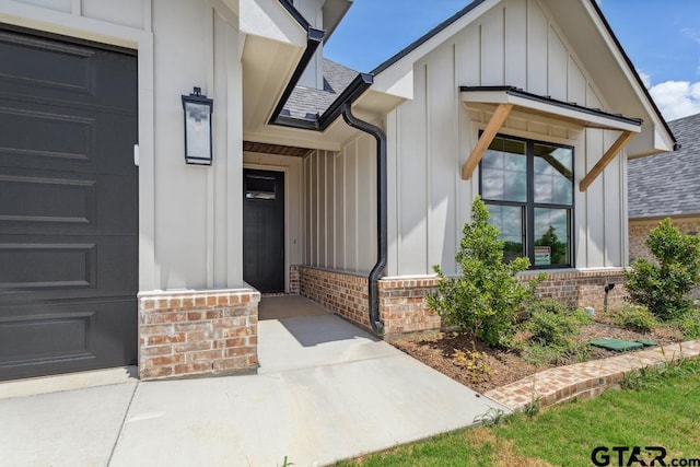 7130 Alexander Dr, Tyler, TX 75707 - view of exterior entry with board and batten siding, brick siding, roof with shingles, and a garage