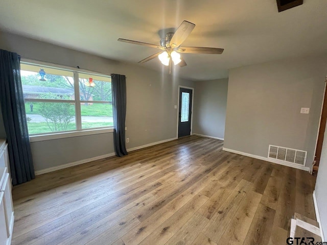 spare room featuring baseboards, visible vents, wood finished floors, and a ceiling fan
