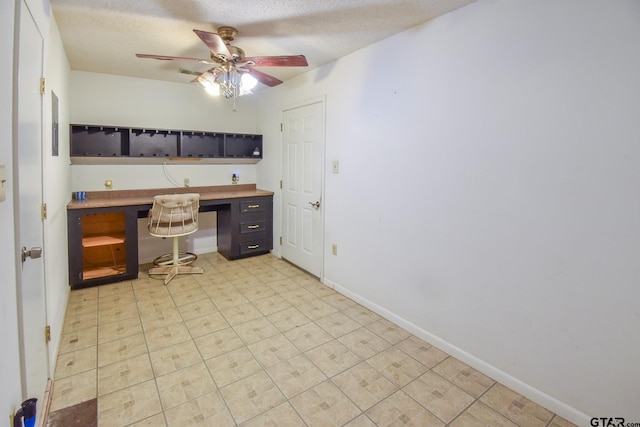 office space with built in desk, ceiling fan, and a textured ceiling