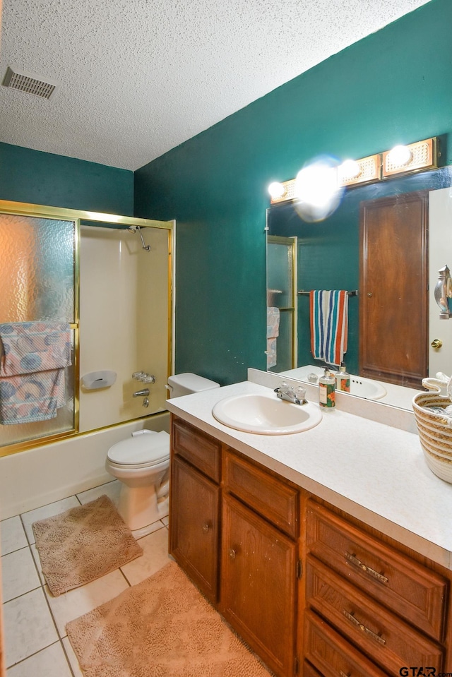 full bathroom featuring tile patterned flooring, a textured ceiling, shower / bath combination with glass door, vanity, and toilet