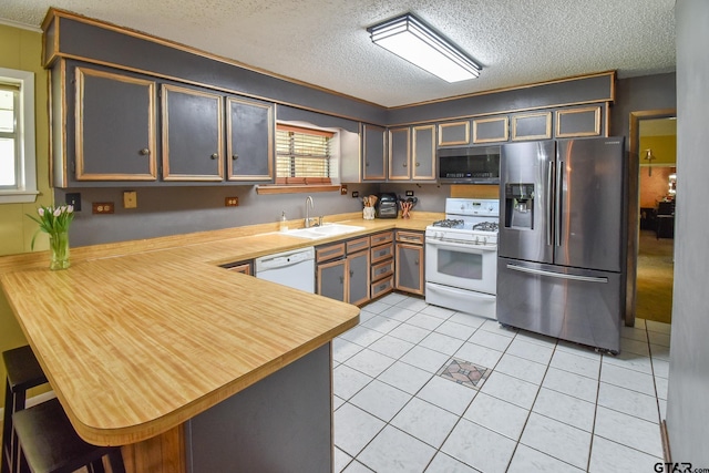 kitchen with kitchen peninsula, a textured ceiling, sink, light tile patterned floors, and appliances with stainless steel finishes