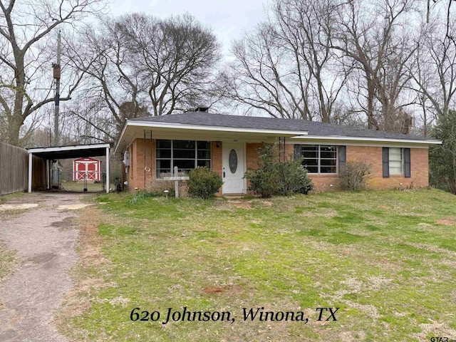 view of front facade with an attached carport, brick siding, fence, driveway, and a front lawn