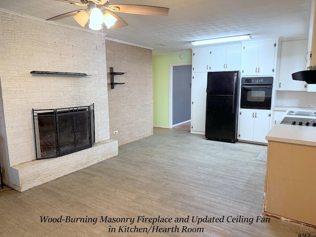 kitchen featuring a fireplace, light wood finished floors, light countertops, white cabinetry, and black appliances