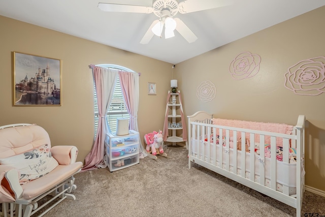 carpeted bedroom featuring ceiling fan and a nursery area