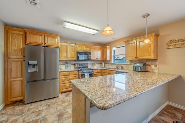 kitchen featuring tasteful backsplash, pendant lighting, kitchen peninsula, sink, and appliances with stainless steel finishes