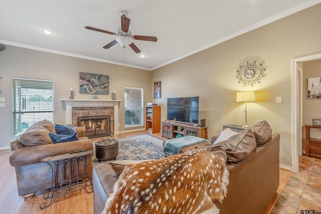 tiled living room with ceiling fan, ornamental molding, and a tiled fireplace