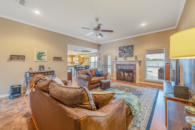 living room with ceiling fan, wood-type flooring, a fireplace, and crown molding