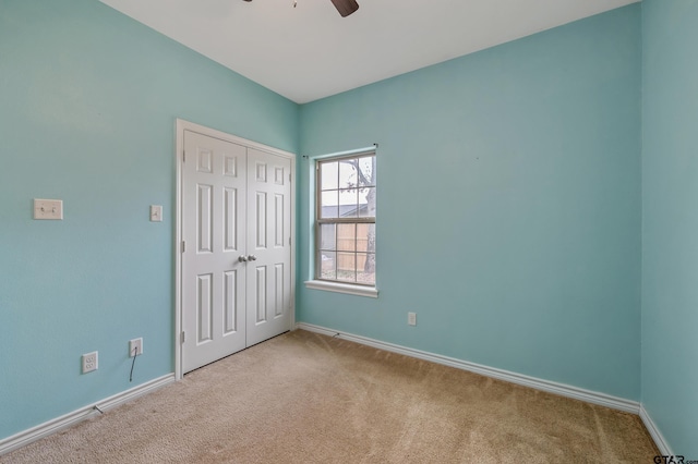 unfurnished bedroom with ceiling fan, a closet, carpet flooring, and baseboards