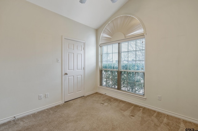 carpeted empty room with vaulted ceiling, ceiling fan, and baseboards