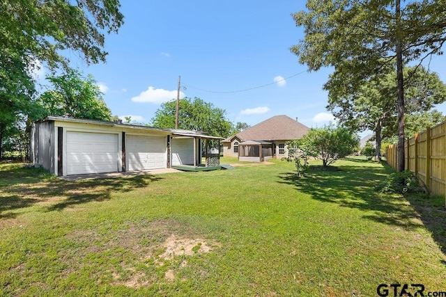 view of yard with fence, an outbuilding, and a detached garage