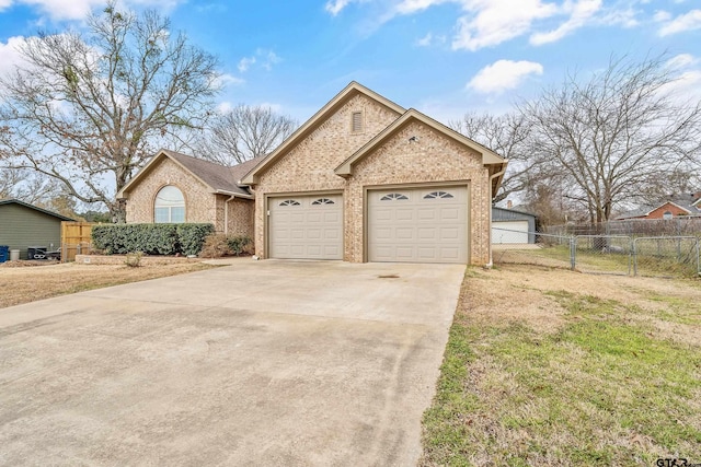 view of front of home with concrete driveway, brick siding, and fence