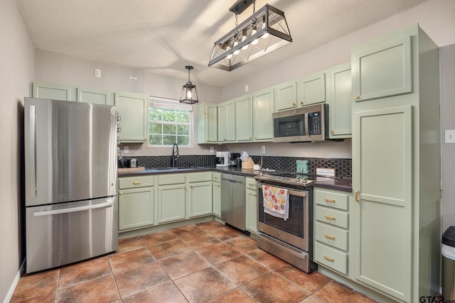 1805 San Saba Dr, Bullard, TX 75757 - kitchen with green cabinetry, appliances with stainless steel finishes, dark countertops, a textured ceiling, and pendant lighting