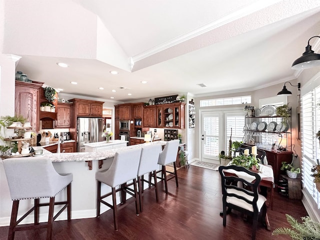 599 N Weldon St, Frankston, TX 75763 - kitchen with stainless steel appliances, a peninsula, a breakfast bar, ornamental molding, and brown cabinetry