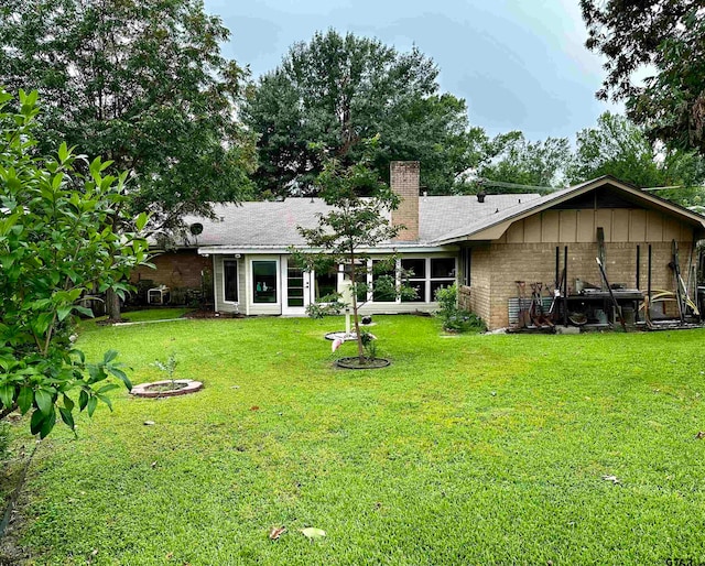 rear view of house with a yard and a fire pit