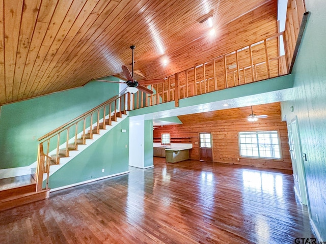 unfurnished living room featuring hardwood / wood-style flooring, ceiling fan, wood ceiling, and wooden walls