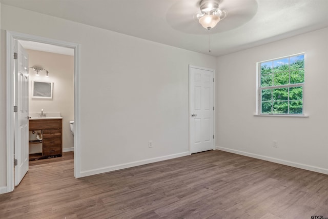 unfurnished bedroom with hardwood / wood-style floors, ceiling fan, and ensuite bathroom