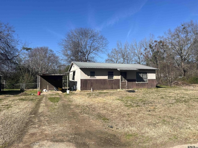 view of front of home featuring dirt driveway, metal roof, and a carport