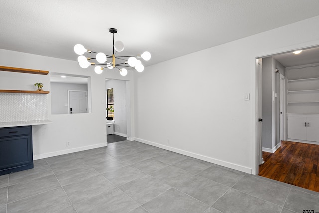 interior space with an inviting chandelier, light tile patterned floors, and a textured ceiling