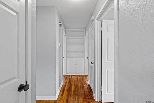 hall with dark hardwood / wood-style floors and a textured ceiling