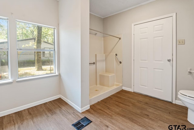 bathroom featuring toilet, a shower, and wood-type flooring