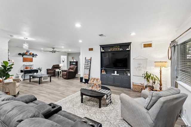 living room featuring wood-type flooring, ceiling fan, and crown molding