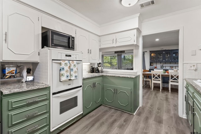 kitchen featuring light hardwood / wood-style floors, white cabinets, tasteful backsplash, crown molding, and double oven