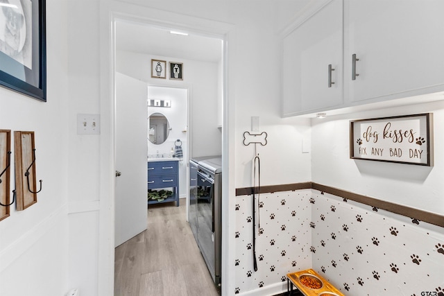 washroom featuring cabinets, light hardwood / wood-style floors, sink, and washer and clothes dryer