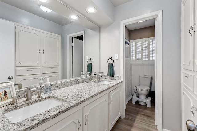 bathroom featuring wood-type flooring, vanity, and toilet