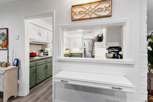 kitchen with stainless steel fridge, crown molding, white cabinetry, green cabinetry, and light hardwood / wood-style floors