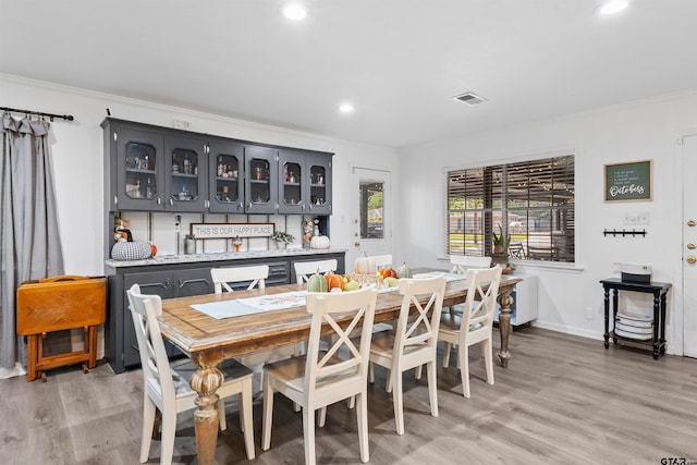 dining space with light hardwood / wood-style floors and crown molding