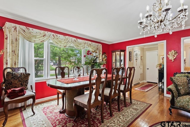 dining room featuring crown molding, baseboards, a notable chandelier, and hardwood / wood-style floors