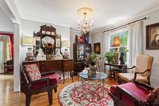 sitting room with an inviting chandelier, crown molding, and wood finished floors