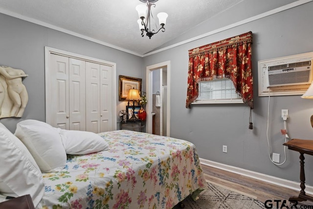 bedroom featuring a closet, lofted ceiling, wood finished floors, baseboards, and a wall mounted AC