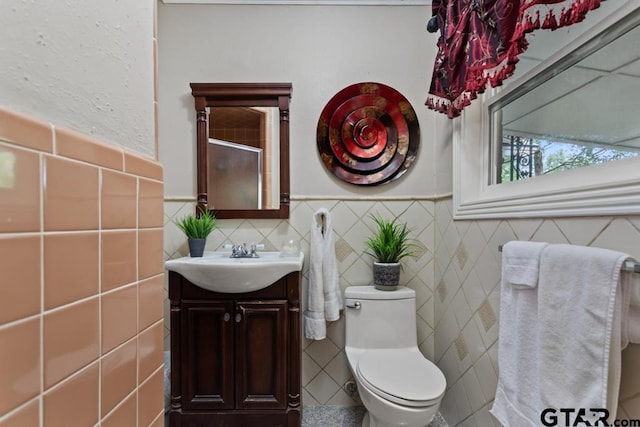 full bath featuring vanity, tile walls, and a wainscoted wall