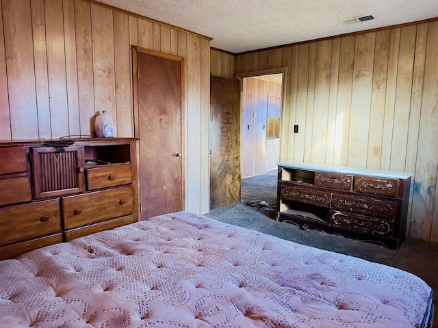 carpeted bedroom featuring a textured ceiling and wooden walls