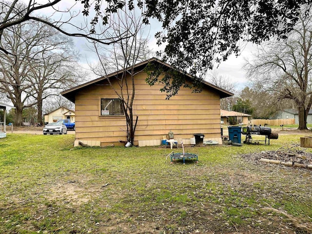 view of side of property featuring a lawn and a trampoline