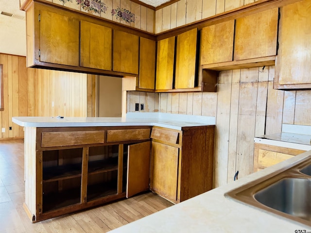 kitchen featuring sink, light hardwood / wood-style flooring, and wood walls