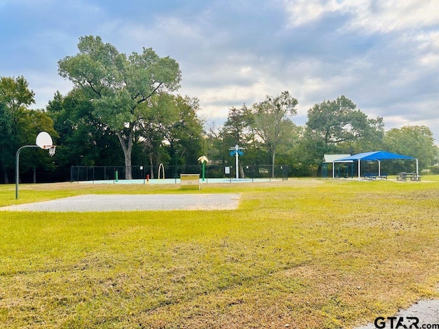 view of home's community with basketball hoop and a yard