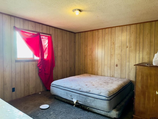 bedroom with carpet flooring, a textured ceiling, and wooden walls