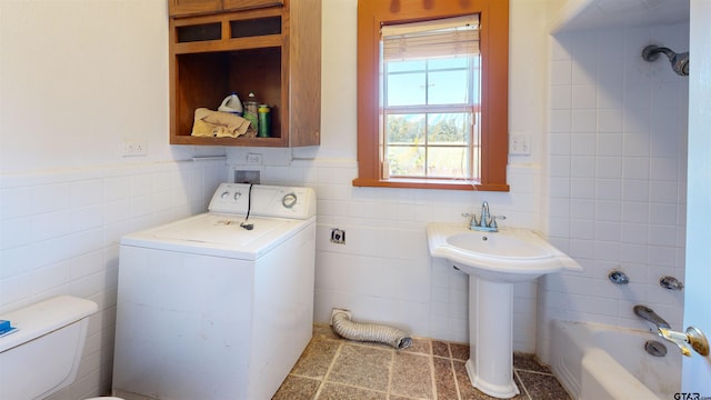 bathroom with washer / dryer, toilet, tile walls, and sink