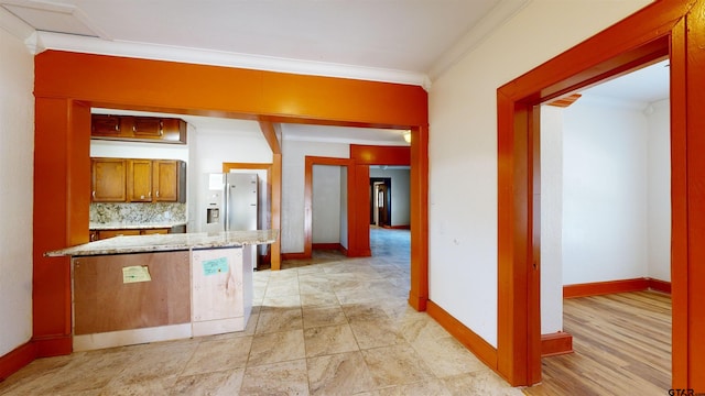 kitchen featuring decorative backsplash, white fridge with ice dispenser, light stone countertops, and crown molding