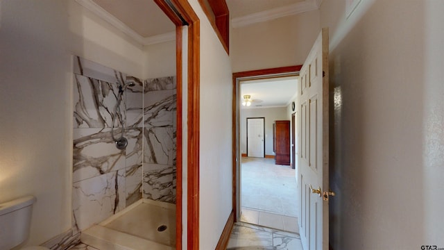 bathroom featuring toilet, ornamental molding, and tiled shower