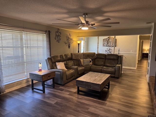 living room featuring ceiling fan, dark hardwood / wood-style flooring, and a textured ceiling