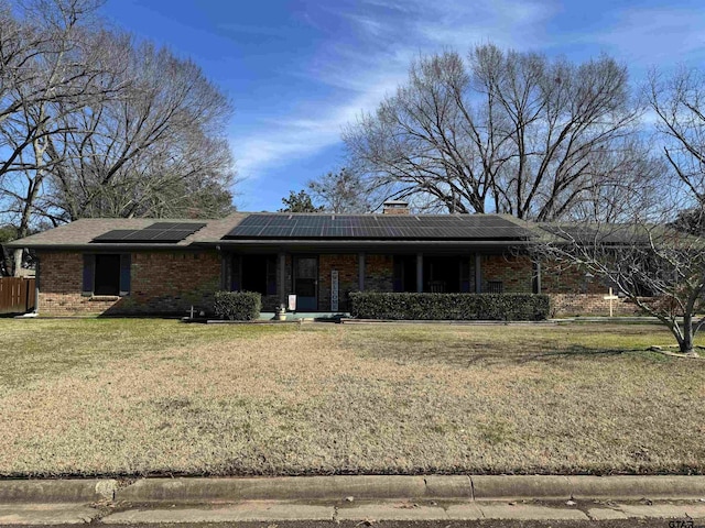 ranch-style house with solar panels and a front yard