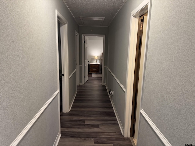 hallway featuring a textured ceiling, dark hardwood / wood-style floors, and ornamental molding